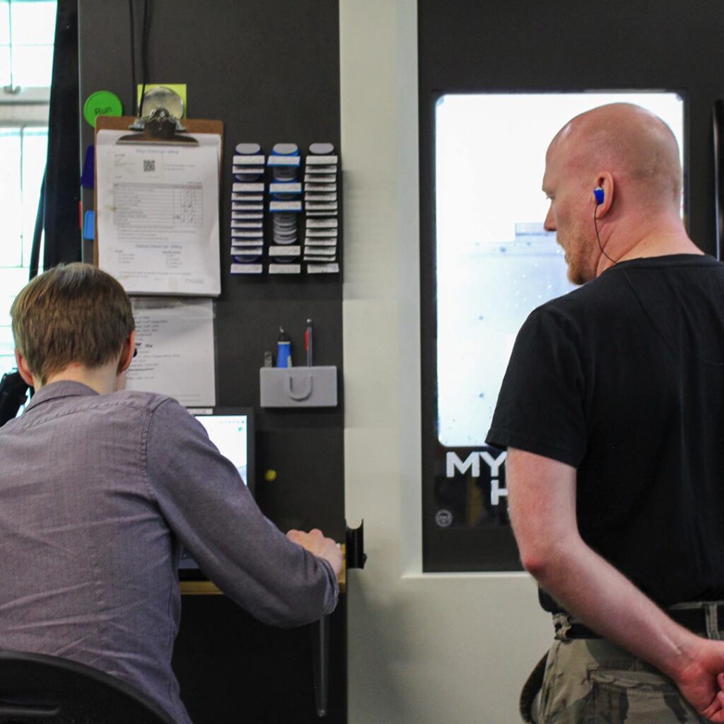 Focus Manufacturing shop floor 07 Two machinists having a conversation in front of a horizontal milling machine.